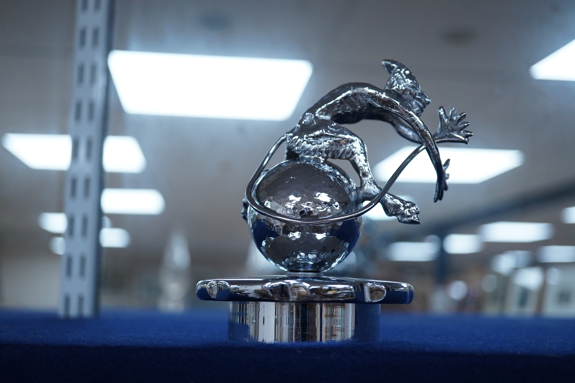 Six chrome and brass car mascots, including; a figure with a dolphin, a figure of Cupid, a grotesque in the form of a devil, a figure of a Tudor gentleman, an Art Deco figure of a flying woman, etc.